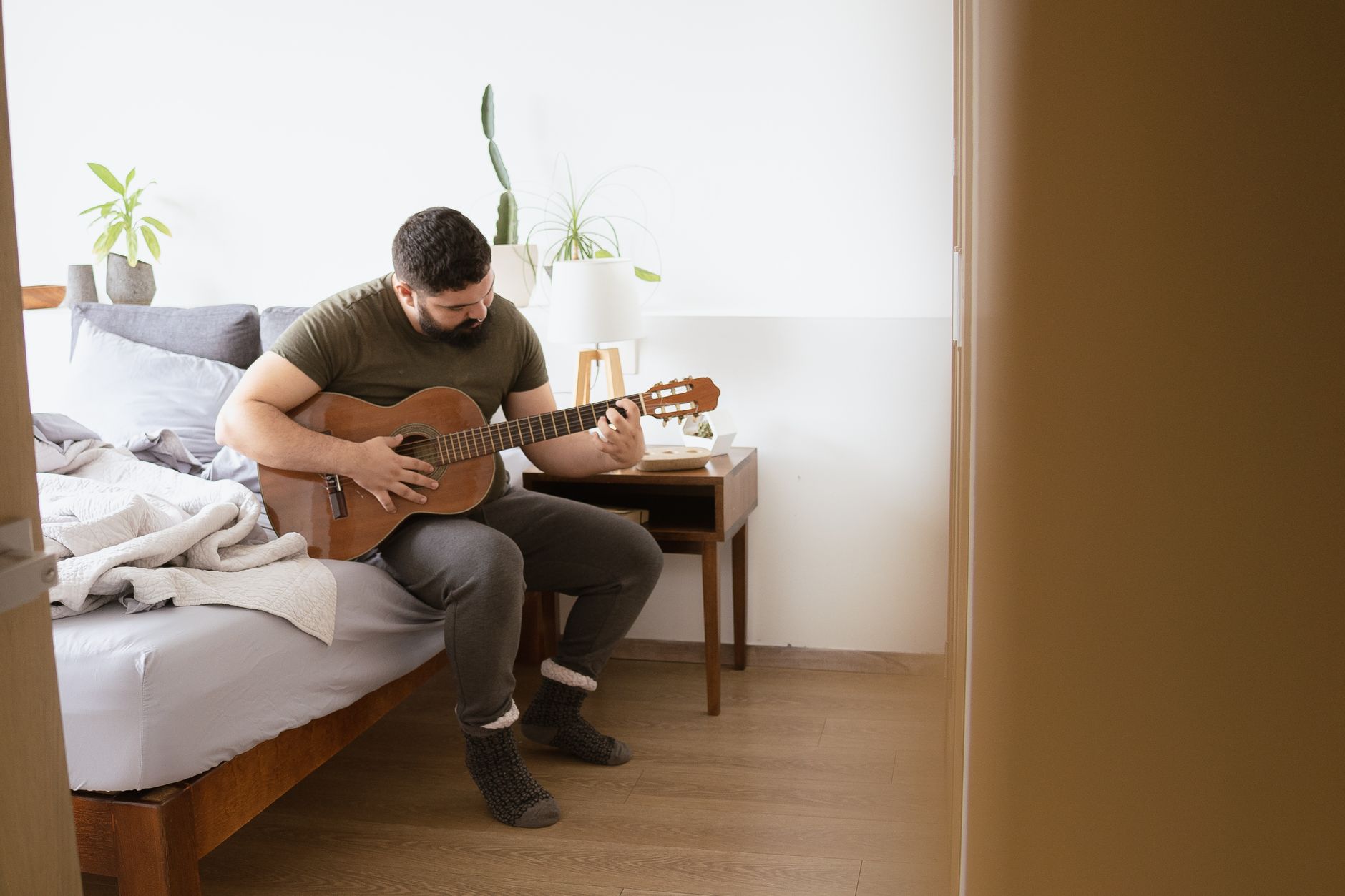 Pourquoi choisir l'apprentissage en autonomie — personne jouant de la guitare acoustique chez soi